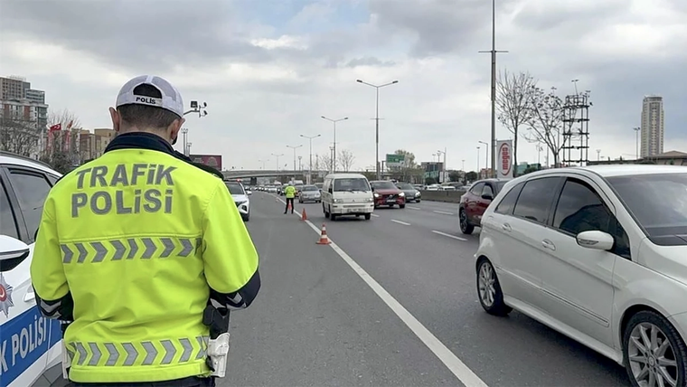 Trafik polisi, yol üzerinde durma talimatı veren bir işaretin önünde duruyor.