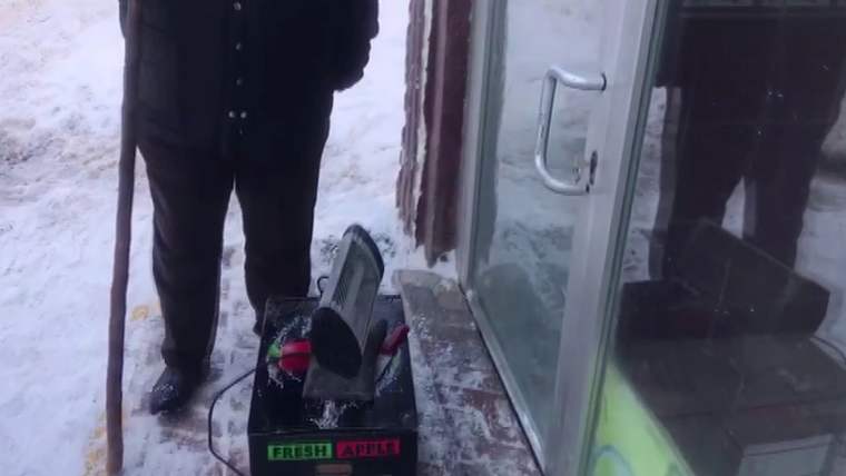 Bir kişi, dükkanın önünde ısıtıcı kullanarak donmuş kilidi açmaya çalışıyor.