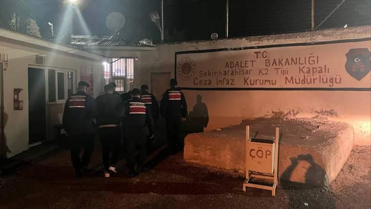 Ceza infaz kurumu önünde, üniformalı polisler binaya doğru yürüyor.