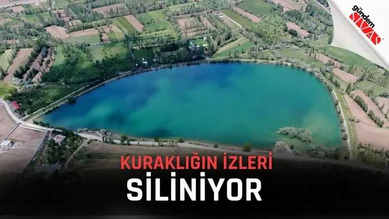 Yeşil alanlarla çevrili bir göl, su seviyesi yükselmiş olarak görünmekte.