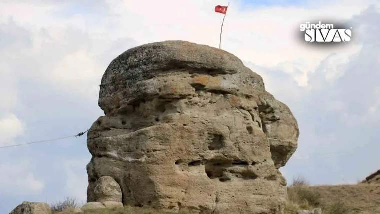 Yüksek bir kayalık üzerinde Türk bayrağı dalgalanıyor.