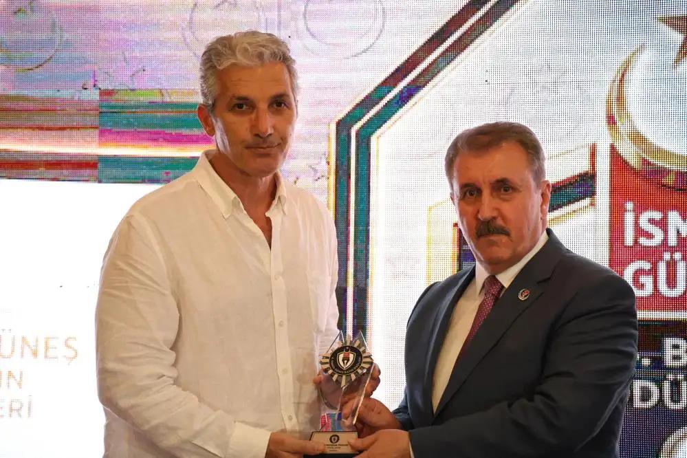 Bir kişi ödül alırken, diğer kişi ödülünü takdim ediyor.