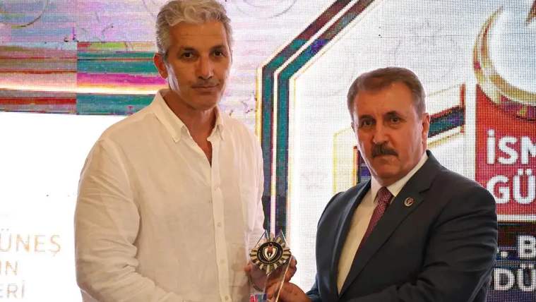 Bir kişi ödül alırken, diğer kişi ödülünü takdim ediyor.