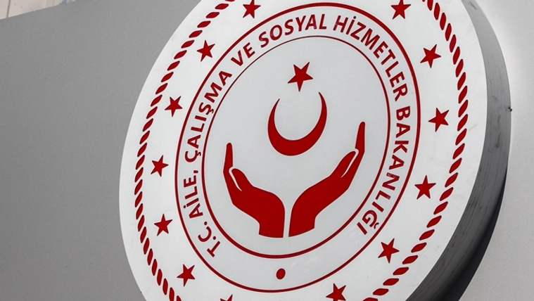 Beyaz dairesel levhada, kırmızı ay-yıldız, yıldızlar ve eller simgesiyle bakanlık amblemi görülüyor.