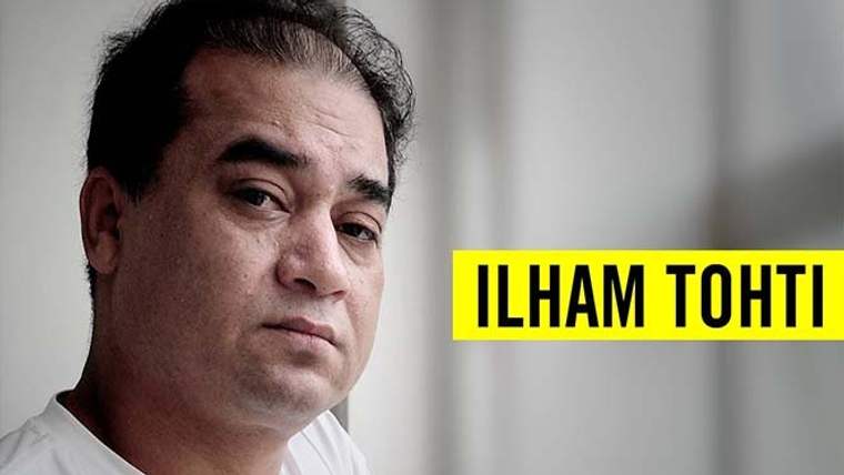 İlham Tohti, beyaz bir arka planda, ciddi bir ifadeyle kameraya bakıyor.