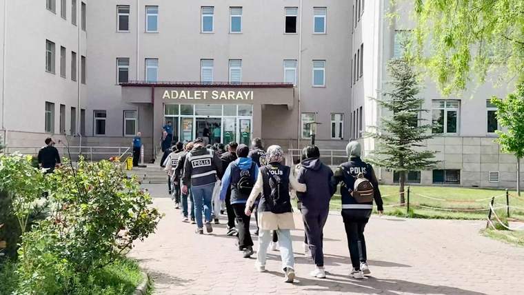 Adalet Sarayı'na doğru yürüyen, üzerinde 'polis' yazılı yelek giyen bir grup insan.