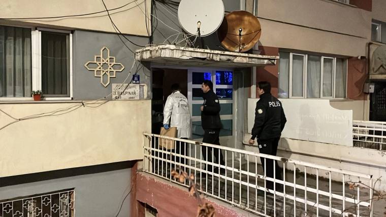 Apartman girişinde iki polis memuru ve beyaz önlük giyen bir kişi, korkulukların arkasında duruyor.