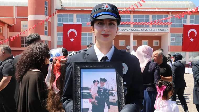 Kep atan bir kadın, elinde babasının fotoğrafını tutuyor. Arka planda Türk bayrağı ve kalabalık görünmekte.