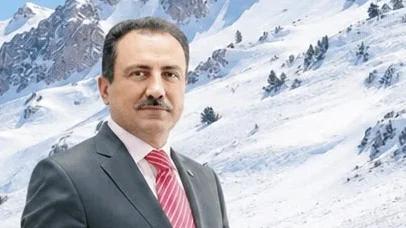 Karla kaplı dağ manzarasında, takım elbise giymiş bir kişi duruyor.