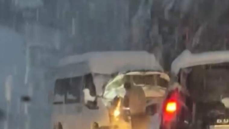 Yoğun kar yağışı altında ilerleyen iki otobüs ve aralarında görülen kırmızı araç, bulanık bir yolda.