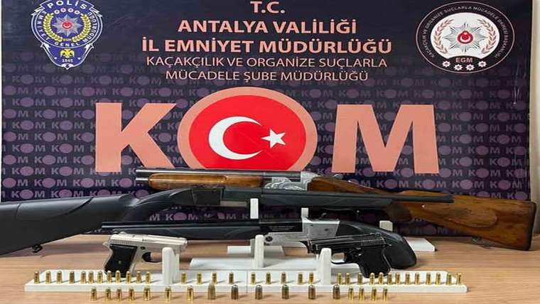 Antalya İl Emniyet Müdürlüğü tabelası önünde iki tüfek, bir tabanca ve dizili mermiler bulunuyor.