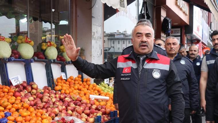 Zabıta ekipleri, meyve tezgahının önünde durarak denetim yapıyor.