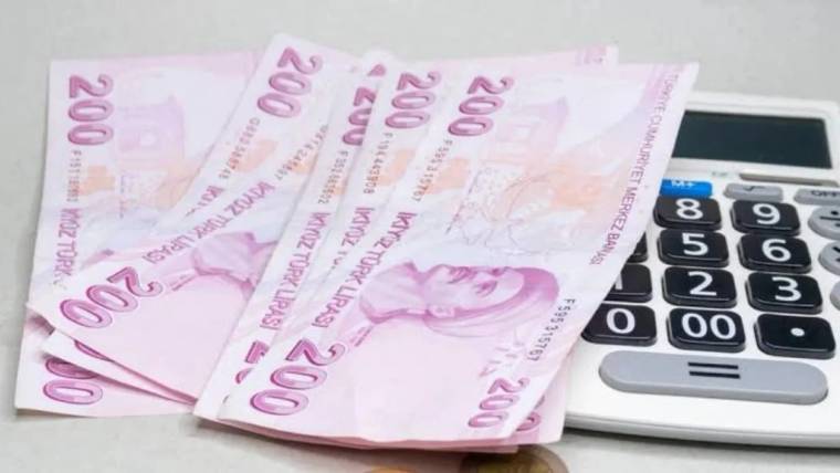 Üst üste duran 200 liralık banknotlar, sağ yanında büyük tuşlu bir hesap makinesiyle birlikte görülüyor.