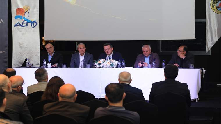 Bir salonda masa başında oturan beş kişi, önlerindeki dinleyicilere karşı panelde yer alıyor.