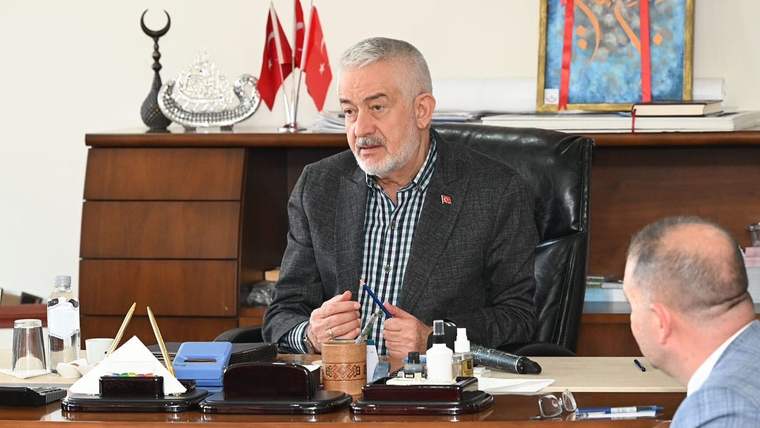 Bir masada oturan bir kişi, önünde çeşitli ofis malzemeleriyle toplantı yapıyor.