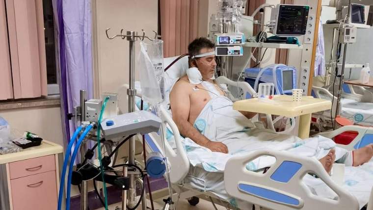 Hastane odasında, ECMO cihazına bağlı bir hasta yatıyor, yanında tıbbi ekipmanlar var.