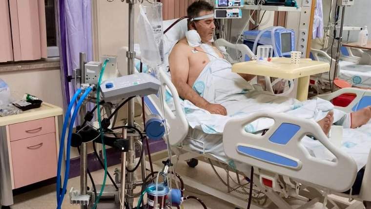 Hastane odasında, ECMO cihazına bağlı bir hasta yatıyor, yanında tıbbi ekipmanlar var.