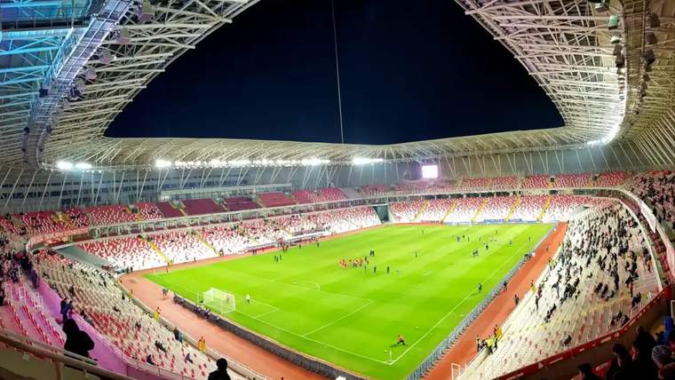 Sivasspor'un stadyumu, yeşil futbol sahası ve boş tribünler görünmekte.