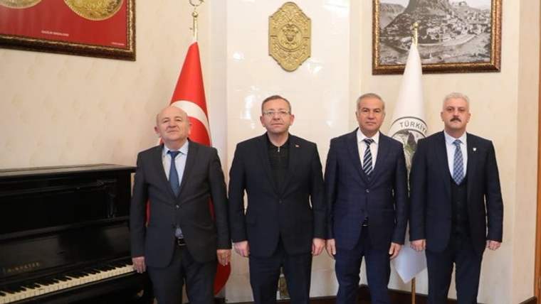 Bir odada yan yana duran dört erkek, Türk bayrağı ve piyano önünde poz veriyor.