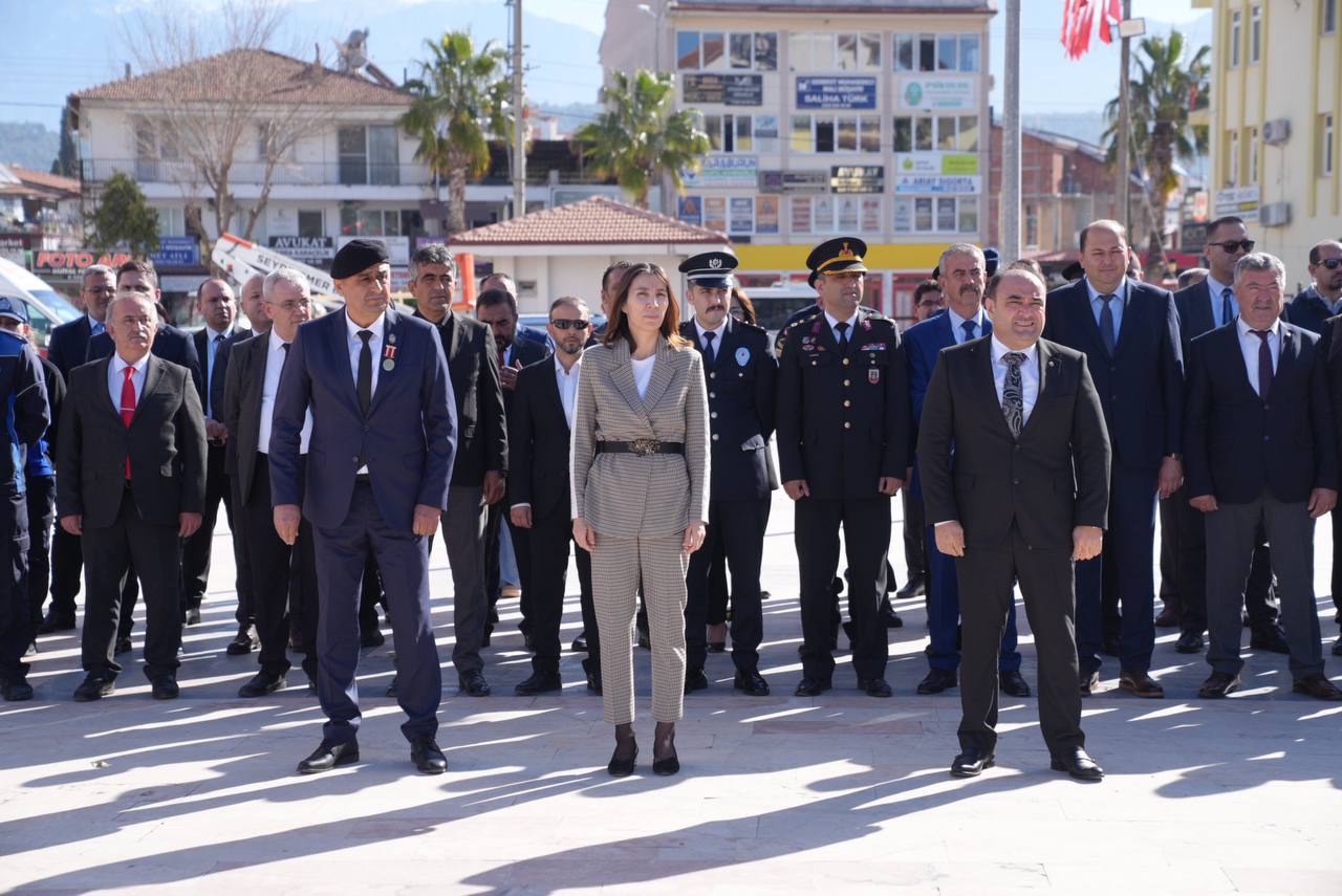 Askerî üniformalı ve sivil giyimli kişiler, açık alanda yan yana yürürken görülüyor.