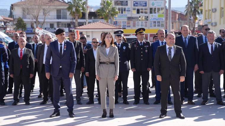 Askerî üniformalı ve sivil giyimli kişiler, açık alanda yan yana yürürken görülüyor.
