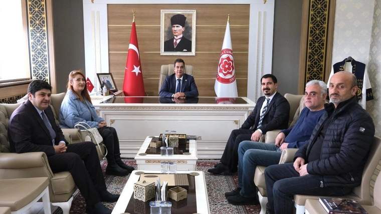 Bir masa etrafında oturan altı kişi, arka planda Türk bayrağı ve Atatürk portresi var.