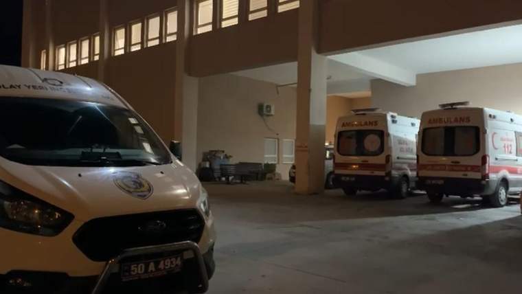 Gece bir binanın girişinde, biri önde ikisi arkada olmak üzere üç ambulans park halinde duruyor.