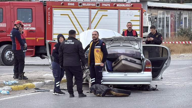 Kaza yerinde, bir otomobilin arka kapak kısmında kurtarma ekipleri çalışıyor.