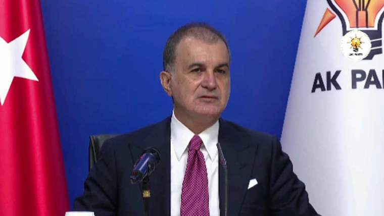 Kürsüde konuşan bir kişi, arkasında Türk bayrağı ve AK Parti bayrağıyla görülüyor.