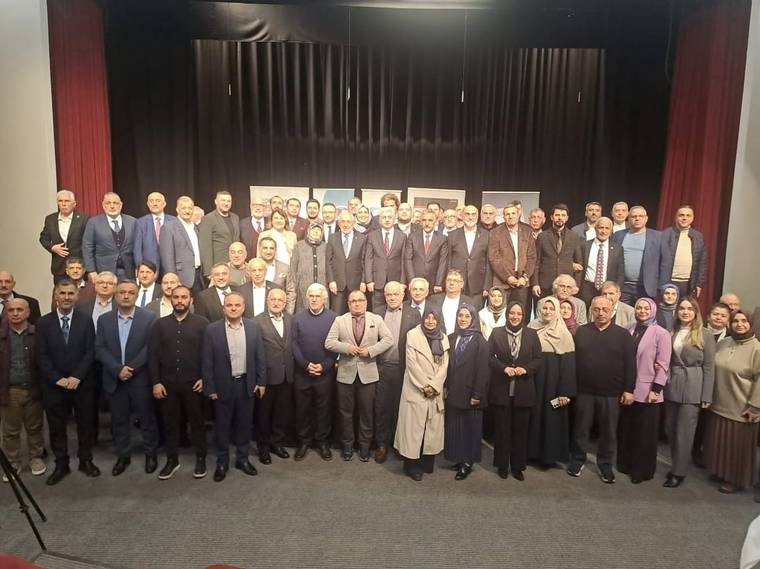 Sahne önünde toplanmış kalabalık bir grup, çeşitli kıyafetler içinde poz veriyor.