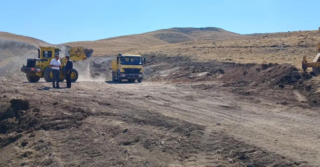 Yol çalışması yapılan alanda bir kamyon ve iş makinesi, işçiler etrafta duruyor.