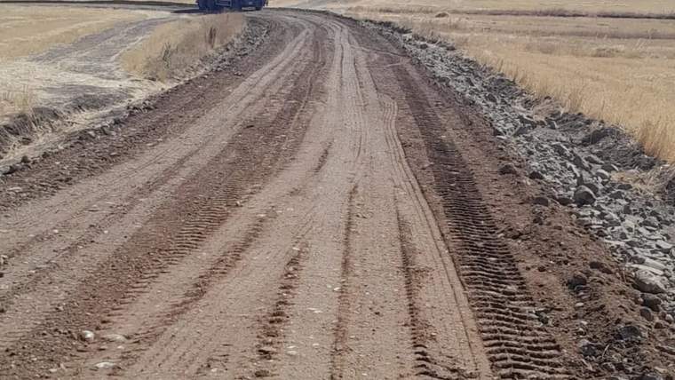 Stabilize yol çalışmaları yapılan bir köy yolu, yan tarafta bir kamyon duruyor.