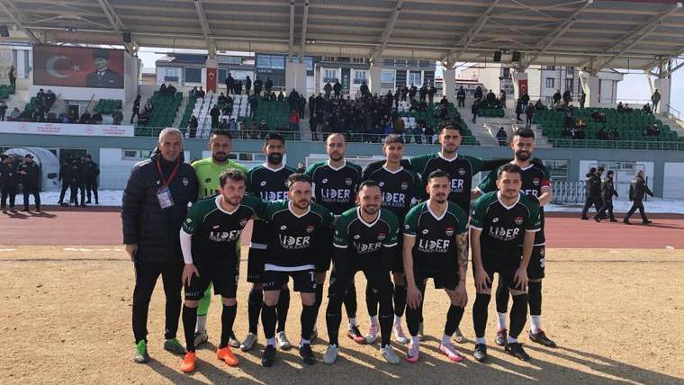 Yeşil-siyah formalar giyen futbolcular, tribünlerin önünde maç öncesi takım fotoğrafı için poz veriyor.