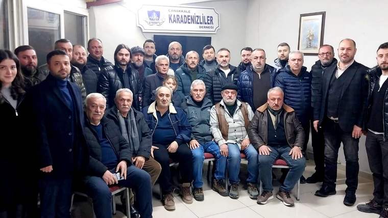 İç mekânda, duvarında “Karadenizliler” yazılı tabela bulunan salonda bir grup insan birlikte duruyor.