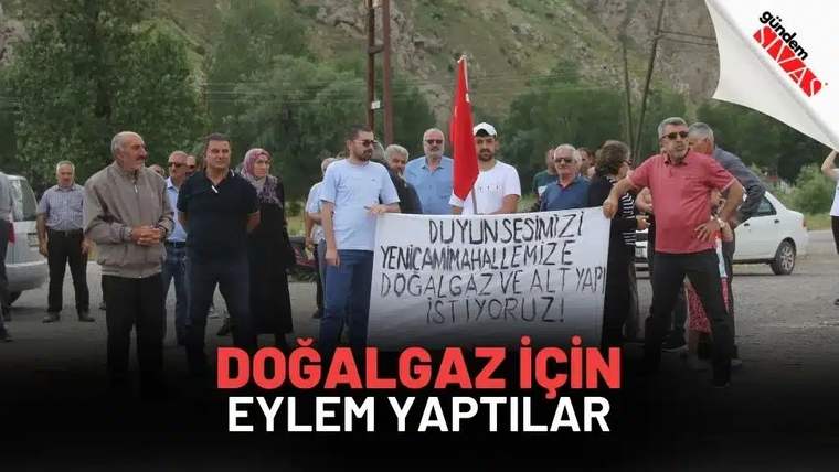 Bir grup insan, üzerinde doğalgaz ve altyapı talebi yazan pankartla açık alanda duruyor.