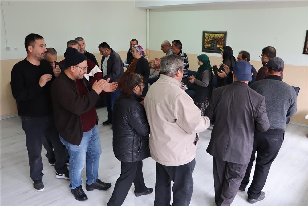 Bir grup insan, bir odada müzik eşliğinde halay çekiyor.