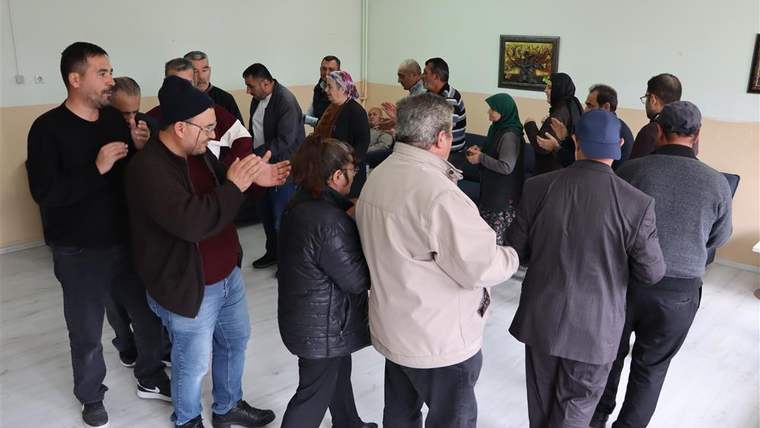 Bir grup insan, bir odada müzik eşliğinde halay çekiyor.