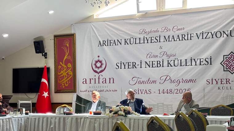 Bir salonda, üzerinde “Siyer-i Nebi Külliyesi Tanıtım Programı” yazılı pankart önünde üç kişi oturuyor.