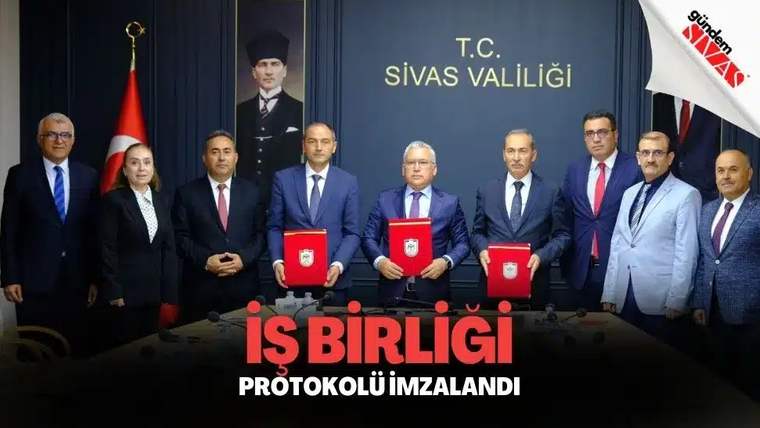 Bir grup insan, masada imza atarak iş birliği protokolü imzalıyor.