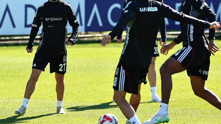 Çim sahada siyah antrenman kıyafetleri giyen dört futbolcu, iki topla çalışma yapıyor.