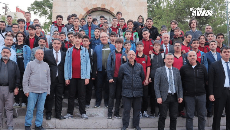 Bir grup genç, bir arada durarak poz veriyor; bazıları resmi kıyafet giymekte.
