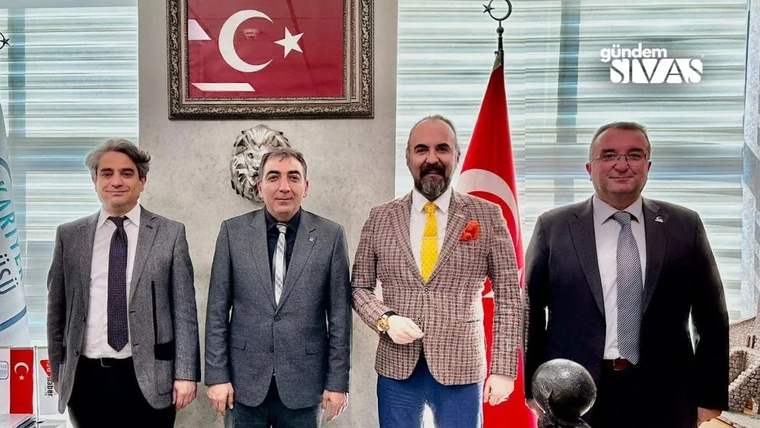 Dört kişi, Türk bayrağı ve Atatürk resmi önünde poz veriyor.