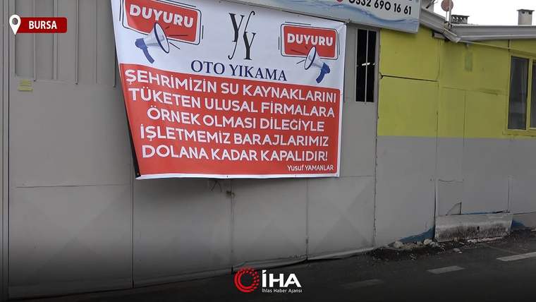 Bir oto yıkama işletmesinin kapısında su tasarrufu için faaliyetlerine ara verdiğini belirten bir pankart asılı.