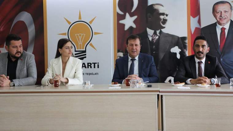 Toplantı masasında dört kişi oturuyor; arkada AK Parti logosu, Türk bayrakları ve Atatürk portresi görülüyor.