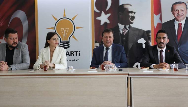 Toplantı masasında dört kişi oturuyor; arkada AK Parti logosu, Türk bayrakları ve Atatürk portresi görülüyor.
