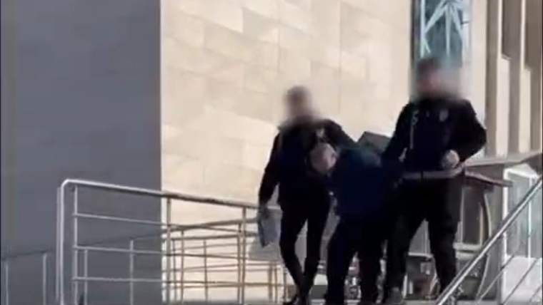 Bina girişindeki merdivenlerde, yüzleri bulanıklaştırılmış üç kişi bir başka kişiye eşlik ediyor.