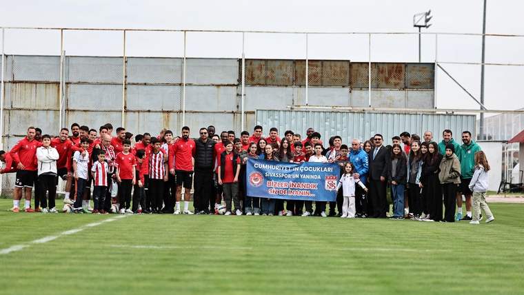 Sivasspor futbol takımı, antrenman sahasında taraftarlarla birlikte poz veriyor.