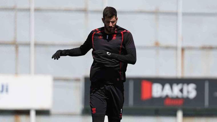 Antrenman yapan bir futbolcu, siyah antrenman kıyafeti giymekte ve eldiven takmakta.