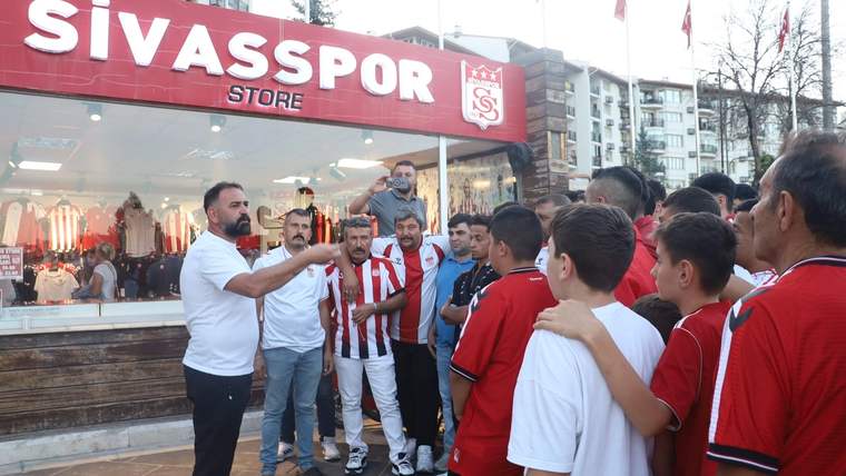 Sivasspor Store önünde, kırmızı-beyaz formalar giyen bir grup ve konuşan bir adam görülüyor.