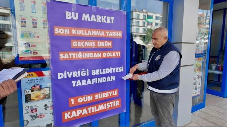 Market girişinde, son kullanma tarihi geçmiş ürün satışı nedeniyle kapatıldığını belirten büyük bir duyuru asılı.